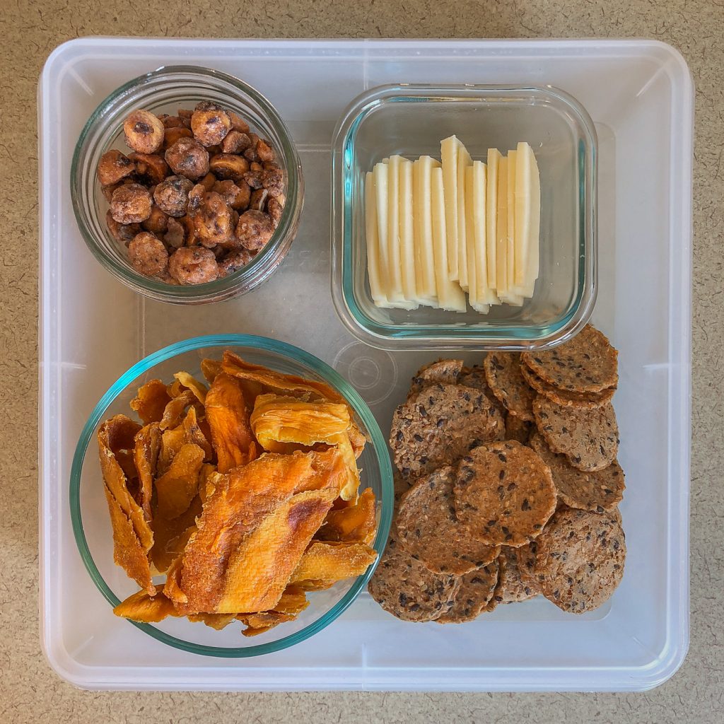 Plastic container with cheese, crackers, nuts and dried fruit